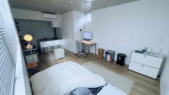 White and wood-toned studio apartment featuring minimal and simple furniture with a cozy atmosphere