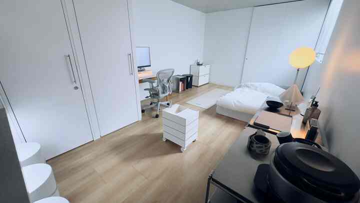 白と木目調の調和があるミニマルな寝室兼ホームオフィス、シンプルで清潔感のある空間