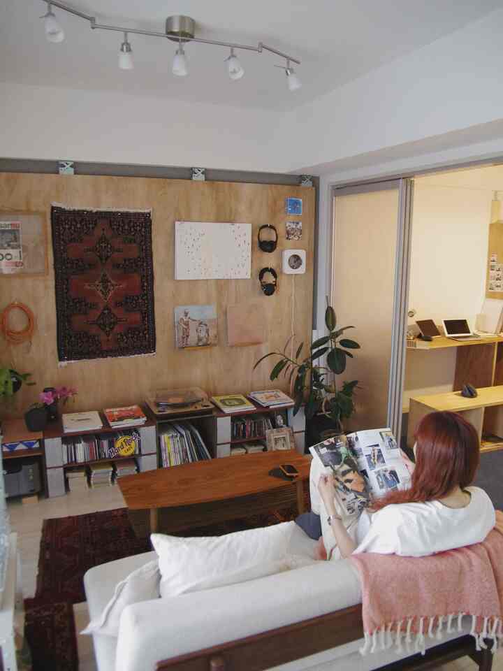 White and natural-toned living room featuring a central sofa and coffee table with wood-paneled wall and cozy decor