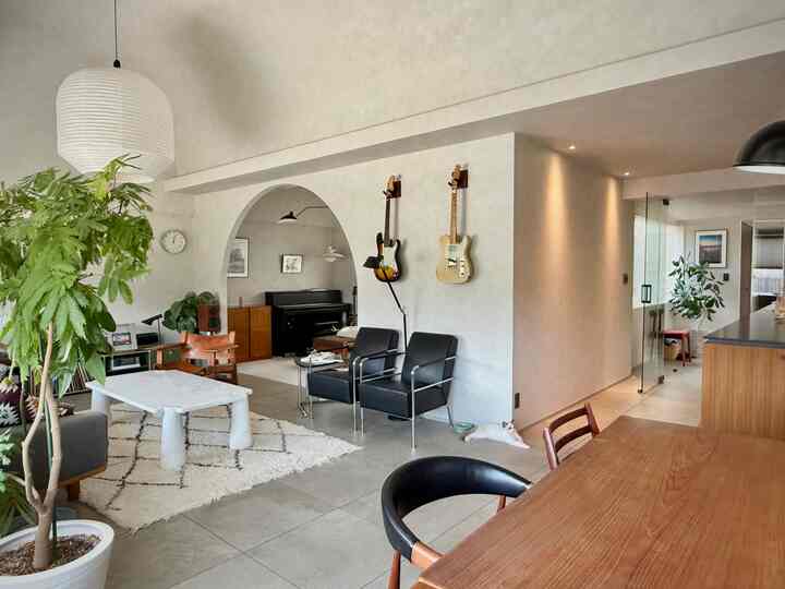 Natural gray and wood tone living room featuring large pendant light, a cat, and vintage furniture creating a warm atmosphere