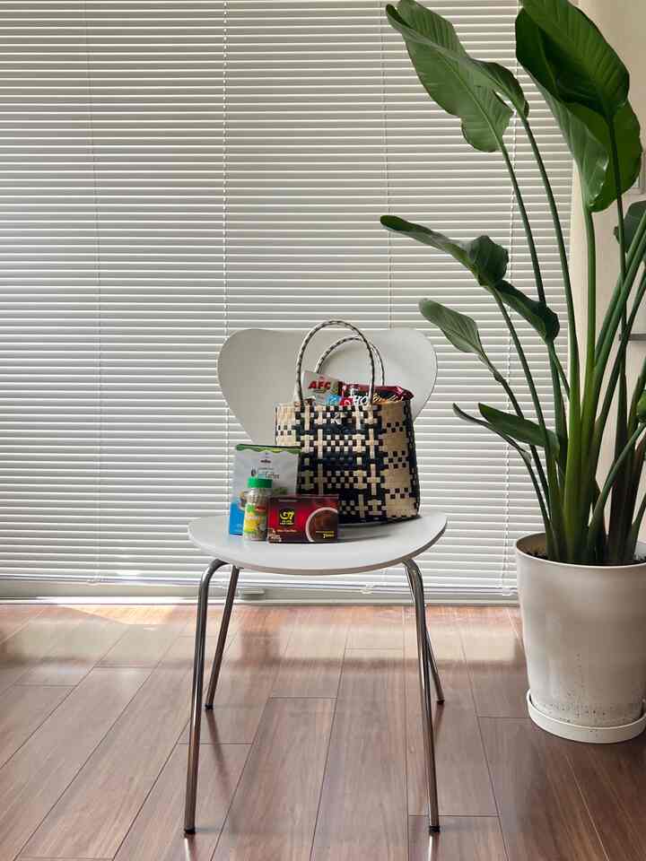明るい白色調のダイニングルーム、ブラインドとダイニングチェア、大きな植物が配置されたナチュラルな雰囲気のインテリア