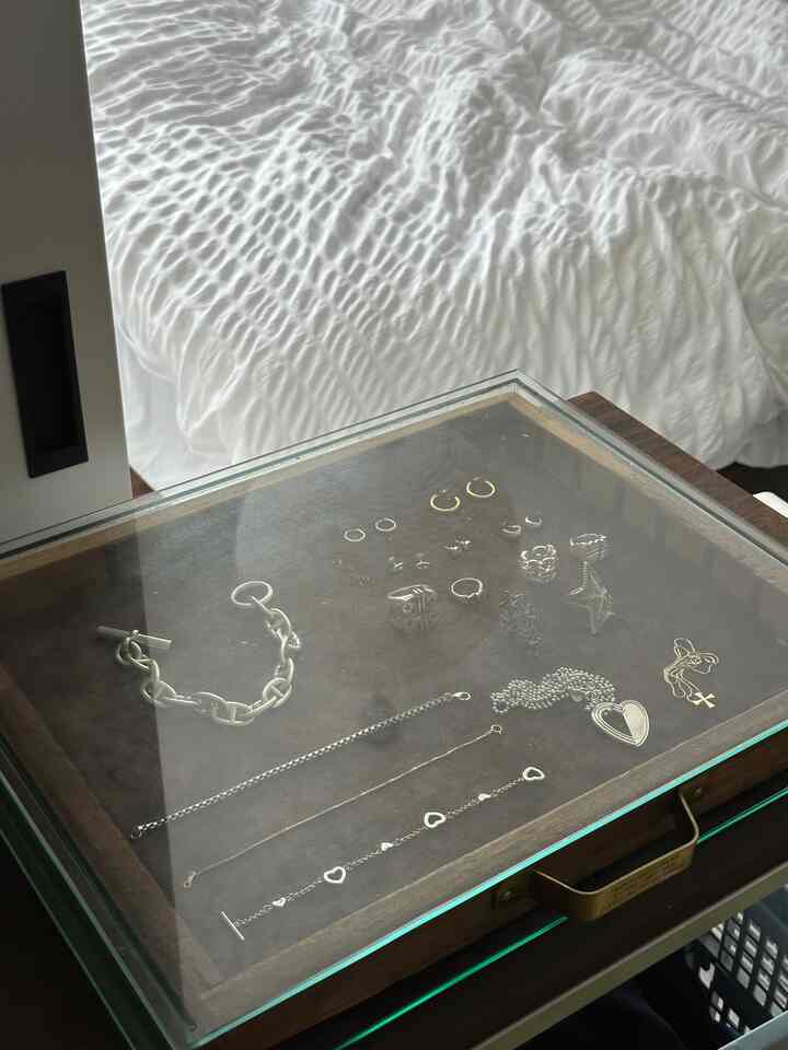 Bedroom space featuring a brown wooden glass display case with various silver accessories on top