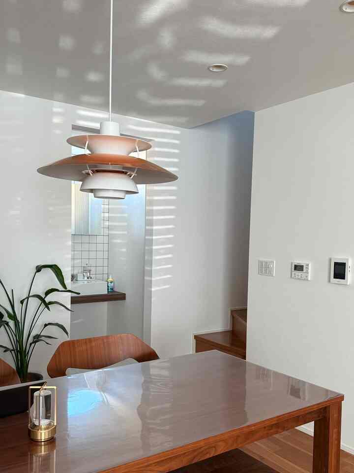 白と木目調の調和が取れたダイニング、ペンダントライトとダイニングチェアが配置された印象的な空間