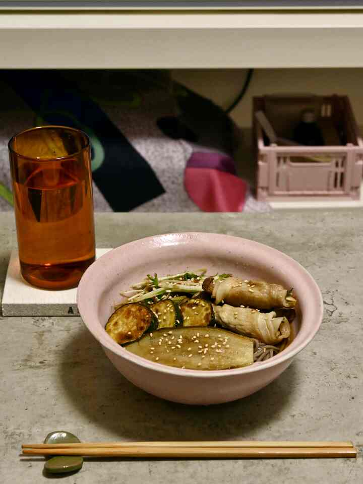 ナチュラルカラーのダイニングルーム、素朴なコンクリートテーブルにピンクの器と箸が配置されたシンプルな空間