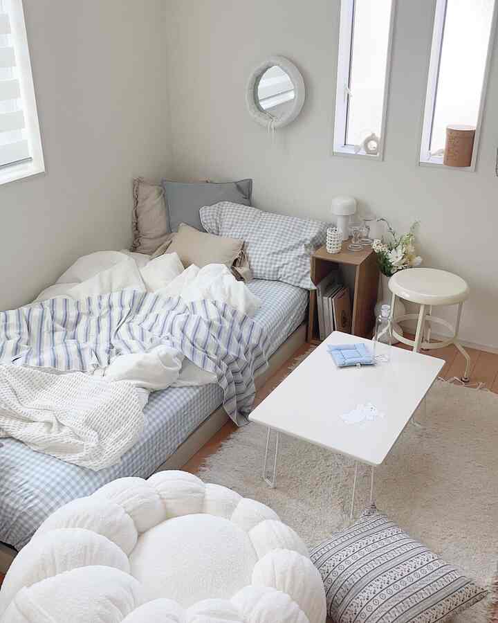 白とスカイブルーの色調の子供部屋、ベッドとラグ、サイドテーブルが配置された自然なモダンな雰囲気のインテリア