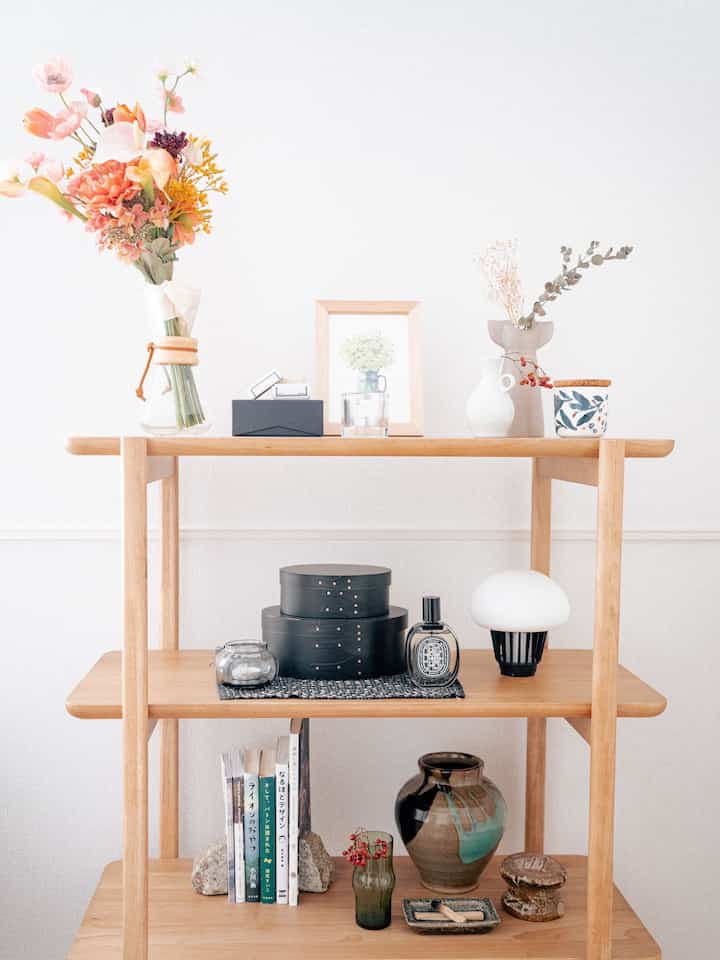 ナチュラルな木目調の棚に花瓶や本、装飾品が調和して配置されたシンプルで雰囲気のあるジャパンディ空間