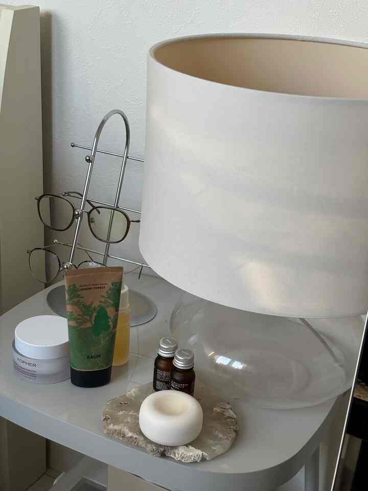 White-toned single household bedroom side table featuring a table lamp and aroma accessories in a neat setting