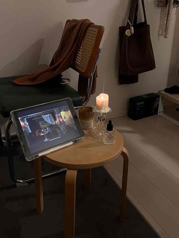 ブラウンとグレーのトーンの小さな空間、ヴィンテージのラタンチェアと木製のサイドテーブルにキャンドルとディフューザーが置かれた居心地の良いインテリア