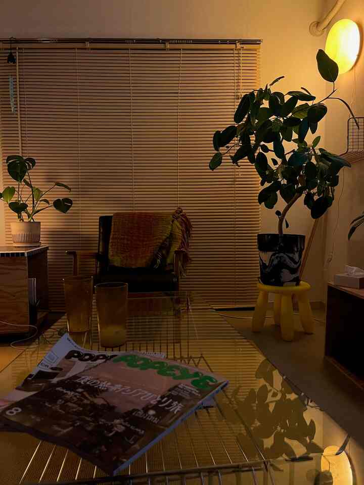 暖かいベージュとブラウンの色調のリビング、中央にコーヒーテーブルとアームチェアが配置され、植物が居心地の良い空間を演出している