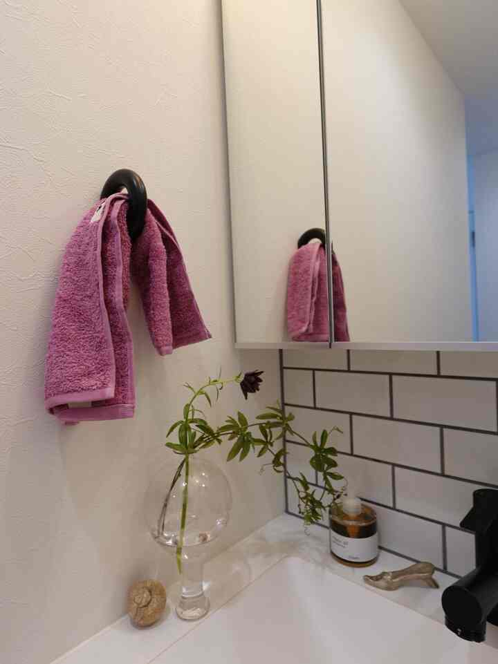 ホワイトタイルとピンクのタオル、透明な花瓶が置かれたナチュラルスタイルの洗面台