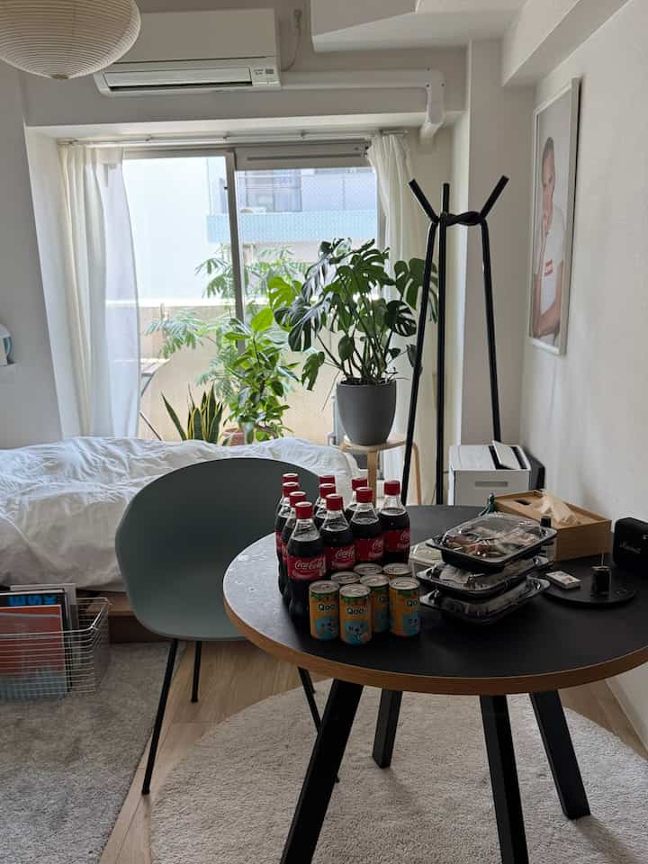A white and black color-themed Nordic-style studio apartment for single occupancy, featuring a large dining table and abundant indoor plants in a cozy interior