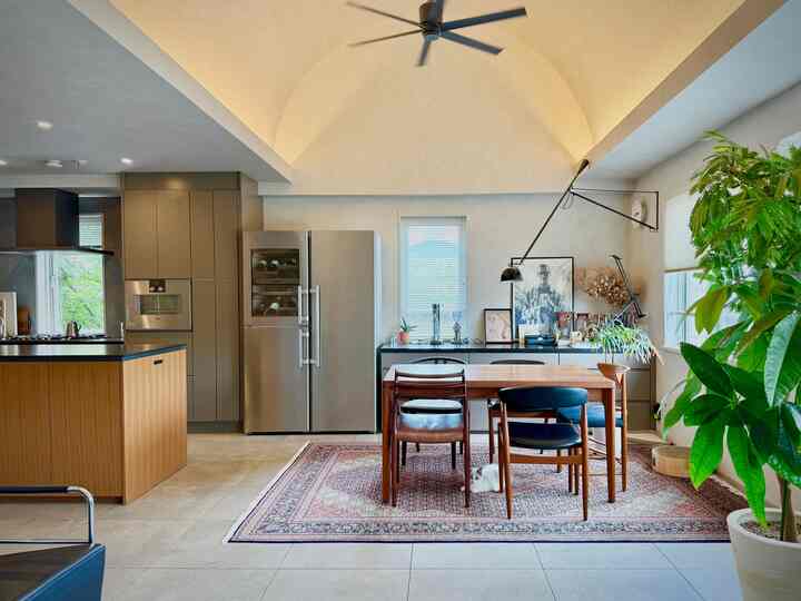 Soft white and wood-tone kitchen and dining area with Persian rug and a cat beneath the table, featuring simple mid-century modern style interior