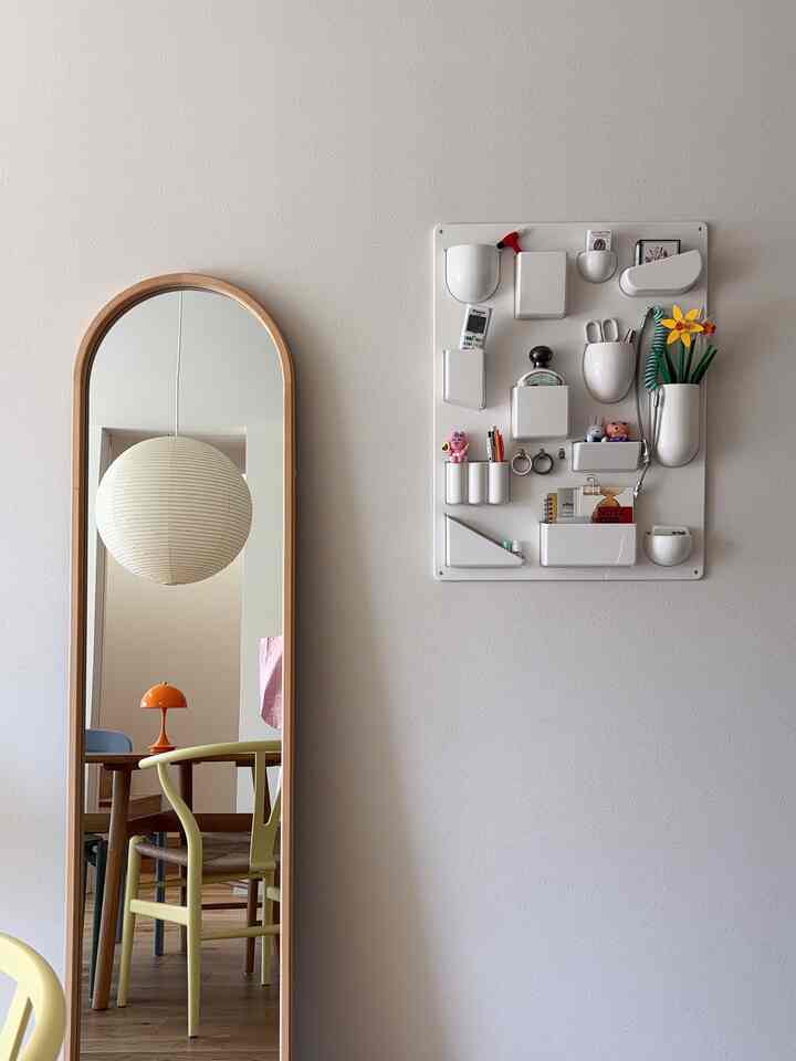 Natural color and wood tone dining room featuring a tall mirror and wall-mounted storage with a clean, Scandinavian vibe