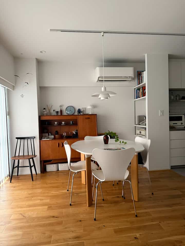 White and wood toned long dining room featuring mid-century modern furniture and vintage cabinet with natural light