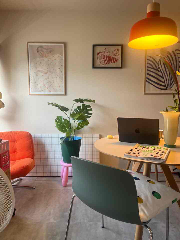 オレンジとグリーンの色調の1LDKリビング、ペンダントライトと丸テーブル、多彩な植物が配置された温かみのあるインテリア