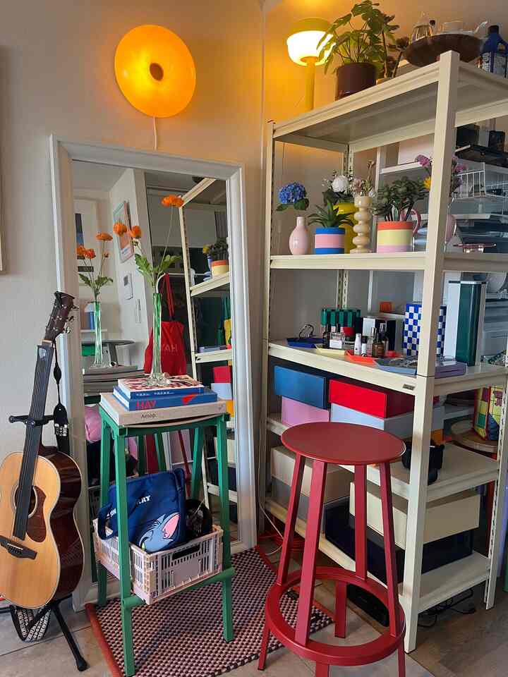 ホワイトの棚とカラフルなバースツール、鏡と植物が配置された落ち着いたミッドセンチュリーモダンの1LDKリビング