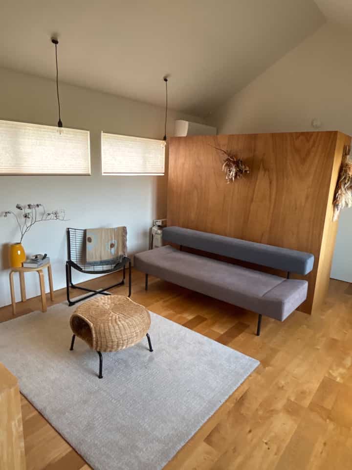 Natural wood tone Nordic living room featuring a gray sofa and rattan stool in a simple, cozy setting