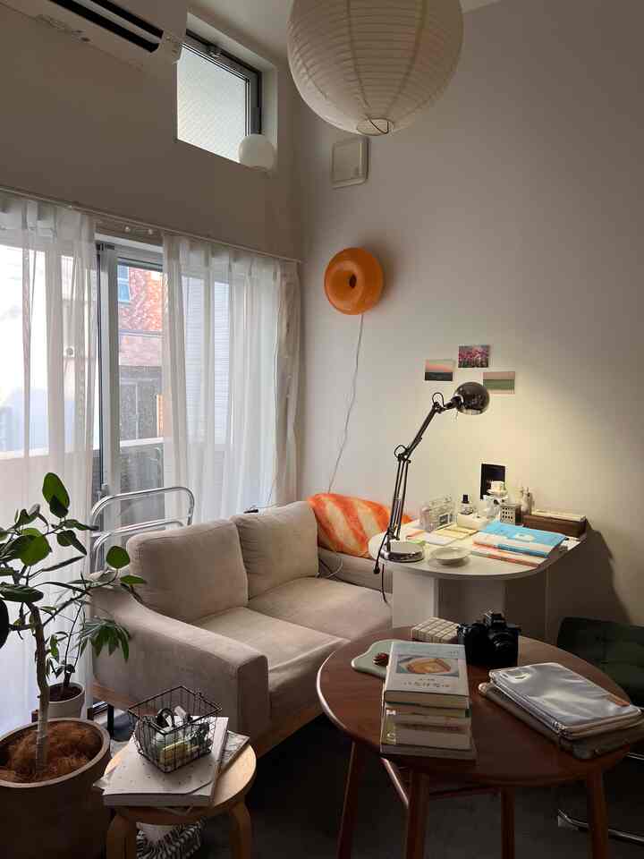 Natural-toned living room with beige sofa, wood brown coffee table, and white curtains creating a cozy, bright atmosphere