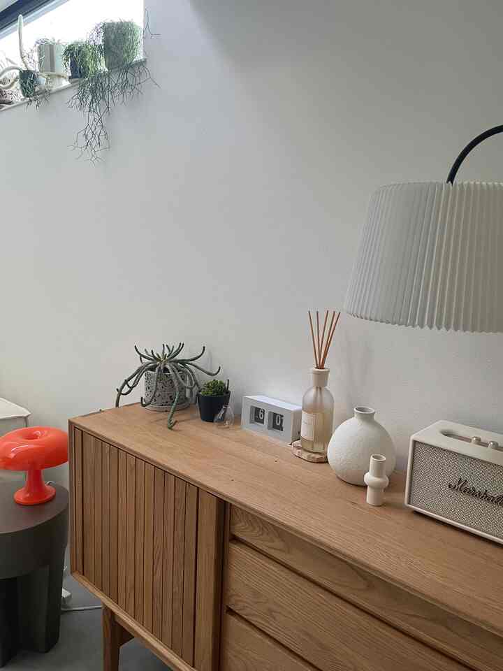 ナチュラルな木目調のリビング、キャビネットの上にディフューザーとスピーカーが配されたシンプルで清潔感のあるインテリア