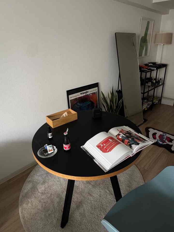 Nordic-style studio dining space featuring a black dining table and beige rug with minimalistic decor