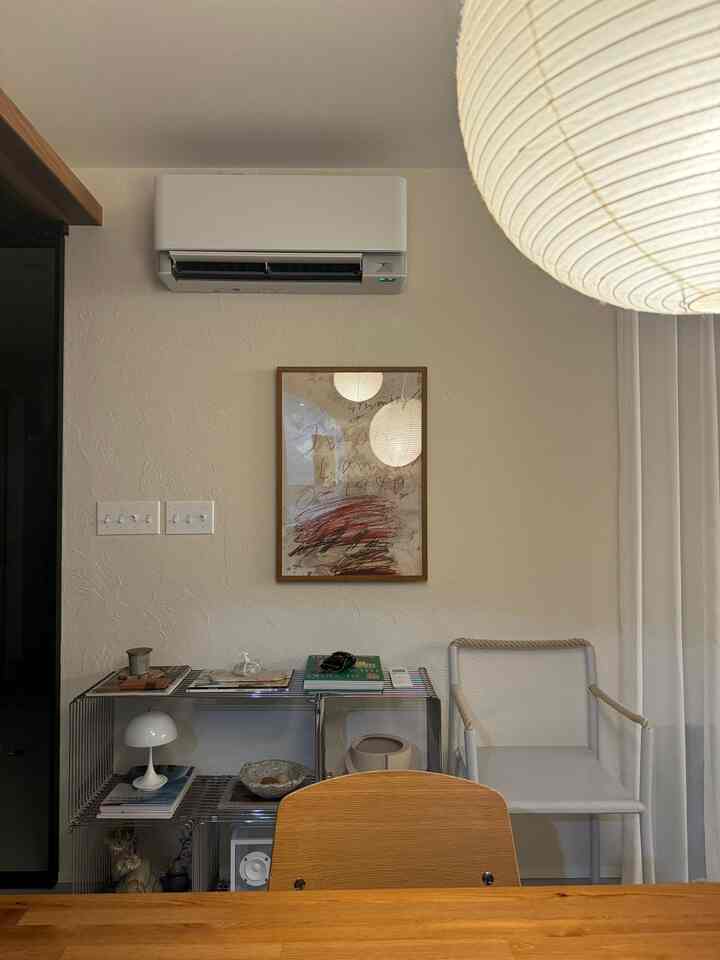 ベージュと白を基調としたミッドセンチュリーモダンのダイニングルーム、木製のダイニングテーブルとメタルシェルフ、大きな丸いペンダントライトが配置された雰囲気のある空間