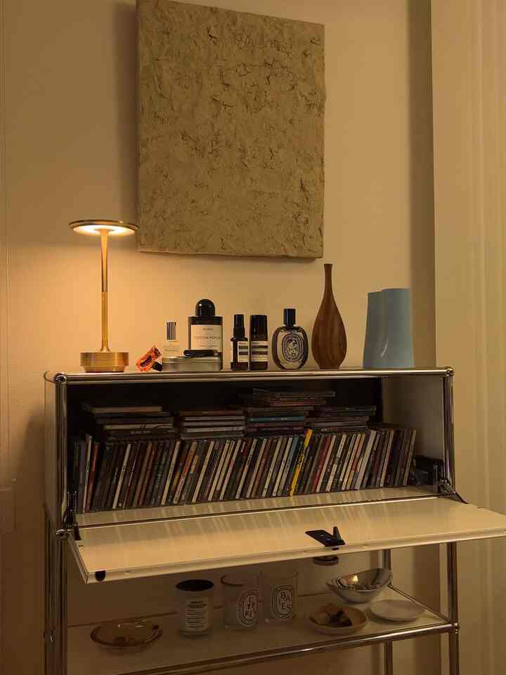 暖かみのあるブラウンとゴールドのトーンが調和するモダンな化粧台スペース、テーブルランプとキャンドルが落ち着いた雰囲気を演出するインテリア。