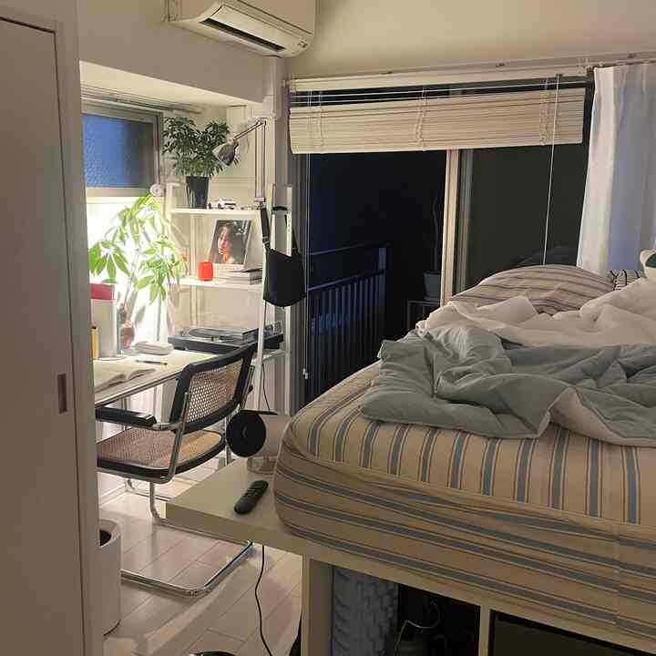 Natural tone 1K bedroom featuring a bed with striped box sheets and a desk, creating a cozy atmosphere