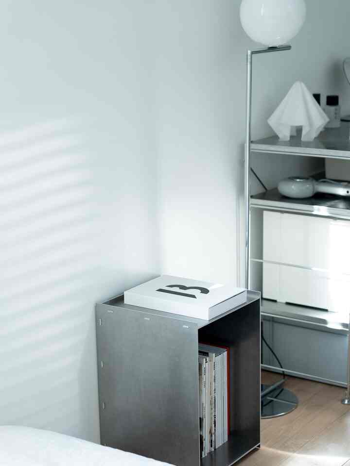 A simple and minimal space in white and gray tones featuring metal storage cabinet and a floor lamp with a clean interior