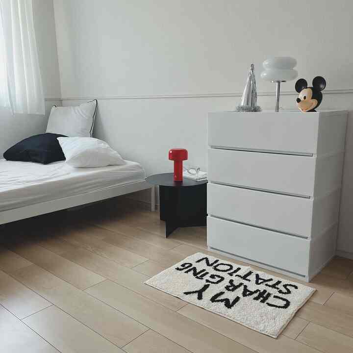 White and black toned bedroom with simple modern furniture and a Mickey Mouse decoration, creating a calm atmosphere