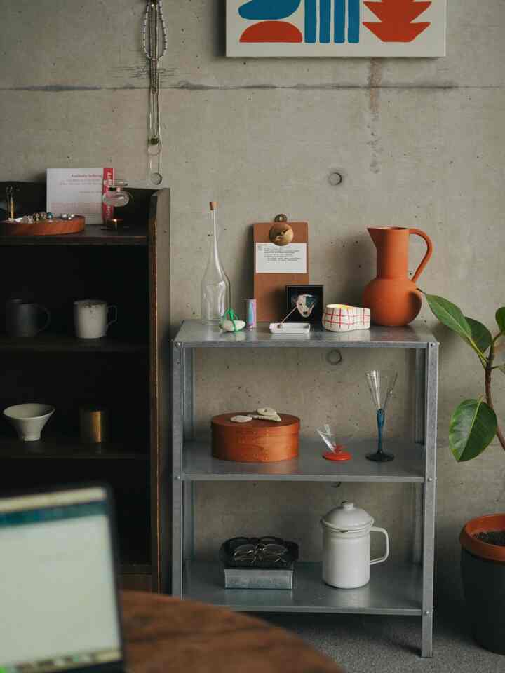 ナチュラルカラーとコンクリート壁が特徴のリビング、イケアの棚と多様な花瓶、植物が配されたモダンなインテリア