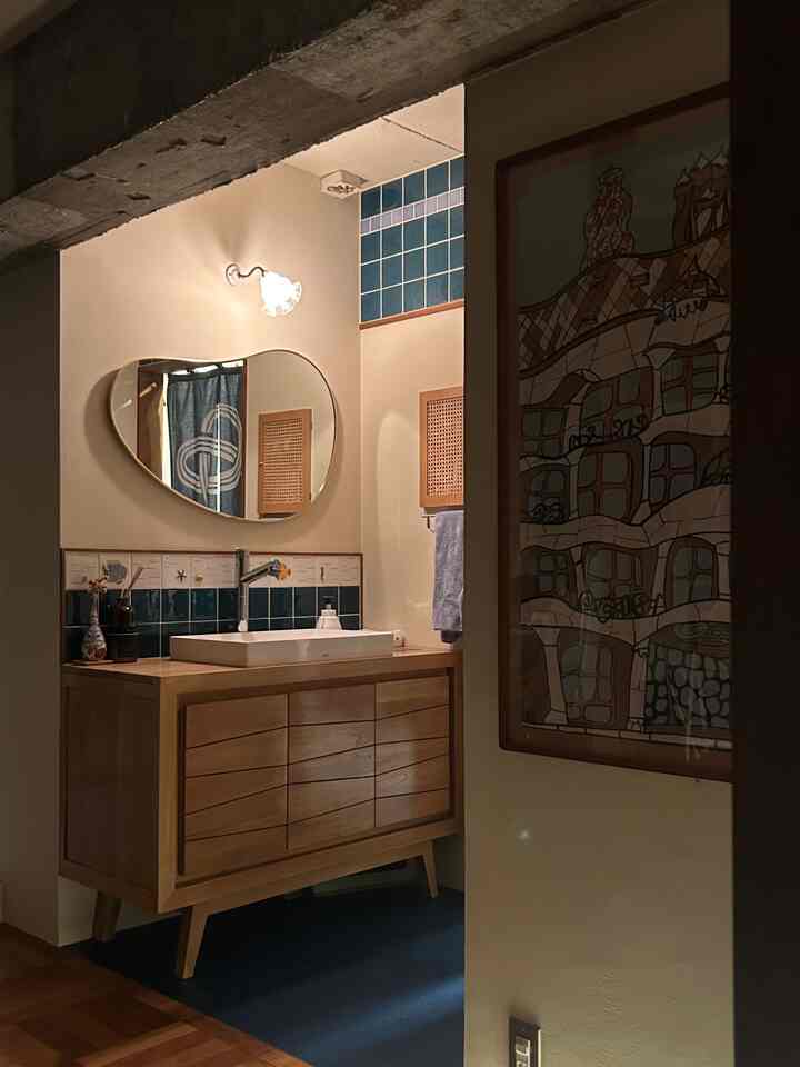 Natural wood tone living area adjacent to bathroom space featuring a washbasin and blue tiled accents