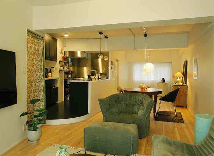 暖かい木目調の床とグリーンのソファが配置されたオープンなワンルームリビング・ダイニング、ヴィンテージとナチュラルモダンが調和する空間