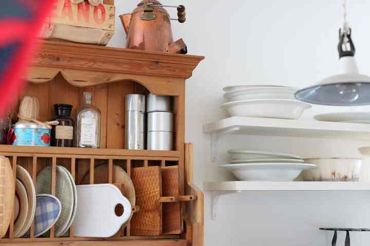 ブラウンウッドと白色のキッチン空間、アンティーク調の皿と収納棚が調和した雰囲気のあるインテリア