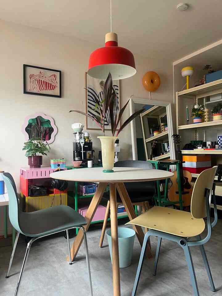 明るくカラフルな1LDKのリビング、丸いダイニングテーブルと多色の椅子が配置されたミッドセンチュリーモダンの印象的なインテリア