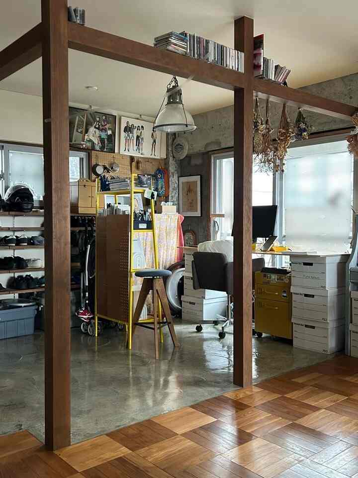 ブラウンの木目調床とゴールドの棚がある狭い書斎、白いデスクとオフィスチェアが配置された雰囲気のある作業スペース