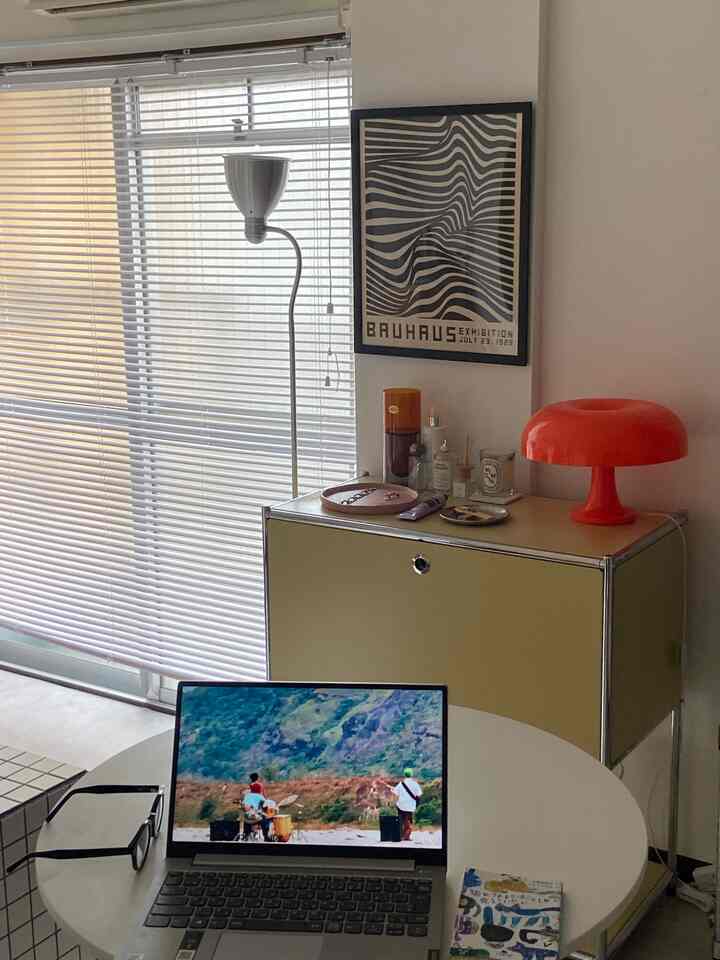 白と黄色のトーンの一人暮らしリビング、ノートパソコンとミッドセンチュリーモダン家具が配置された印象的なインテリア