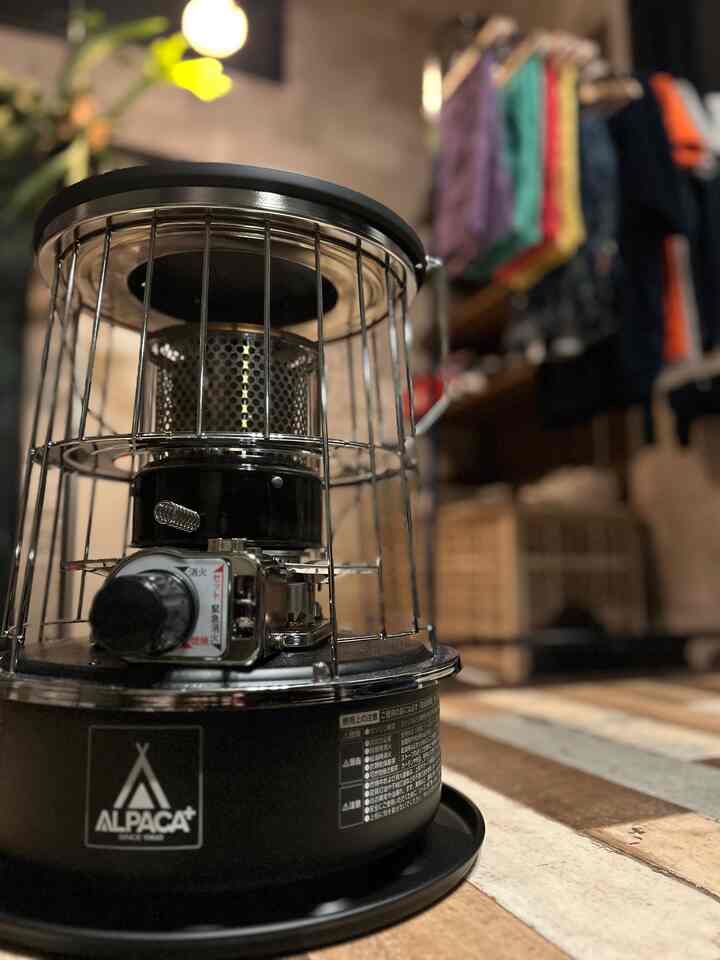 黒いアルパカの小型石油ストーブが置かれた木目調の玄関スペース