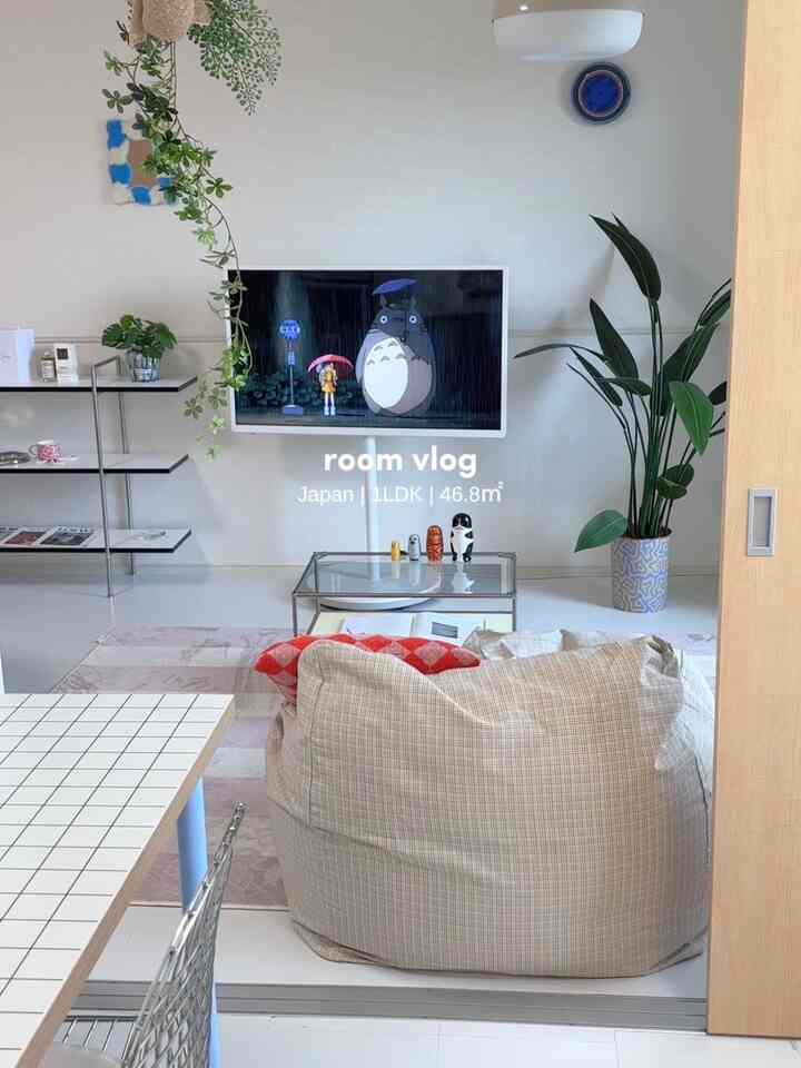 白とナチュラルカラーの1LDKリビング、ベージュのビーズクッションとテレビスタンドが配置されたシンプルでモダンな印象の空間