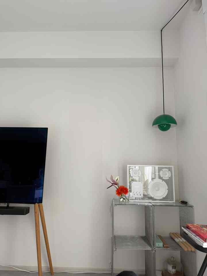 白を基調としたリビング、シルバーのワイヤーシェルフとグリーンのペンダントライトが配置されたモダンで清潔感のある空間