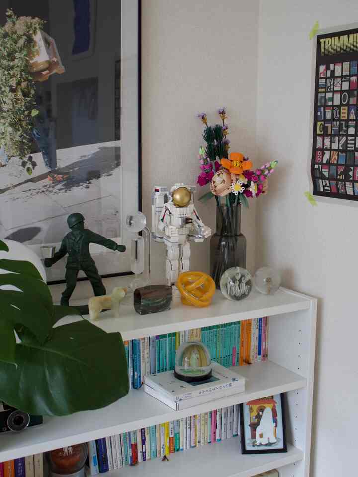 白とナチュラルカラーの北欧風1LDKリビング、植物とミッドセンチュリーモダンのオブジェが配置された雰囲気のある空間