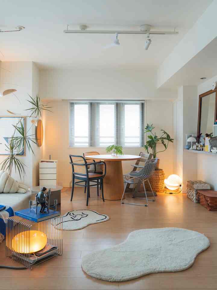 Natural tone living room with white walls and light brown wooden floor, featuring round dining table and mixed chairs creating a cozy cafe-style atmosphere