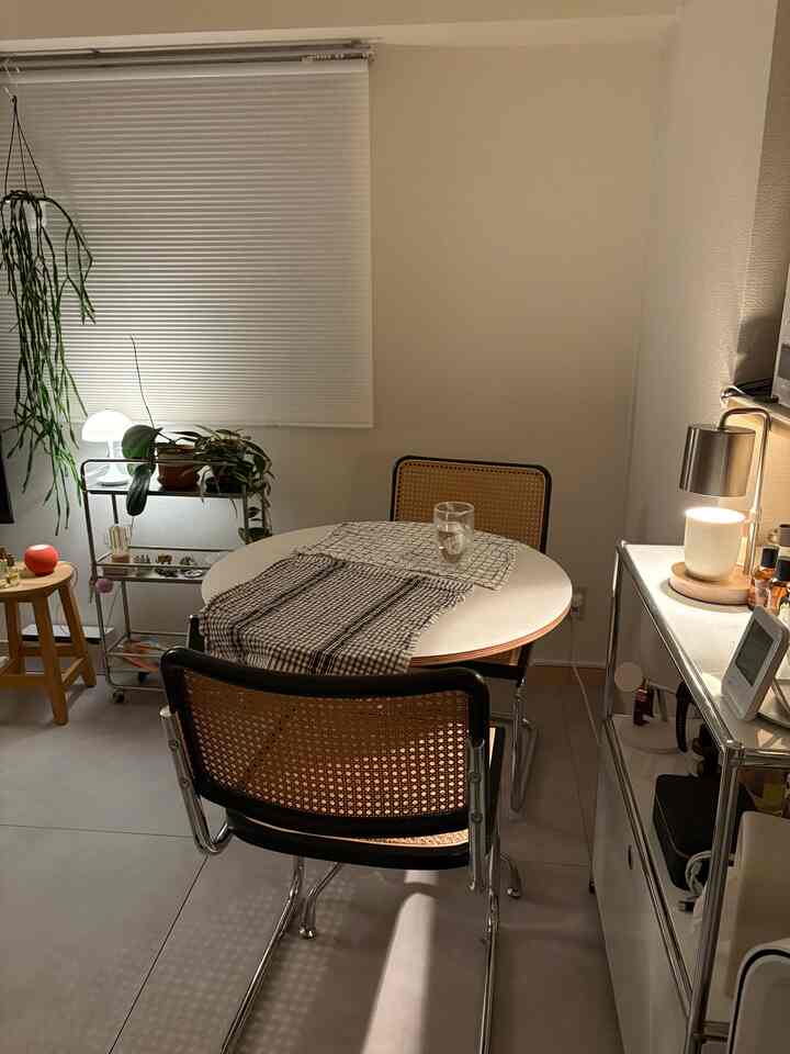 White and brown toned dining room featuring rattan chairs, a round table, and indirect lighting creating a cozy atmosphere