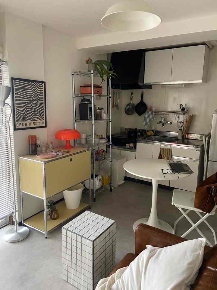白と茶色のトーンの1DKキッチン兼リビング、ミッドセンチュリーモダンの家具とシンプルな収納が調和した印象的な空間