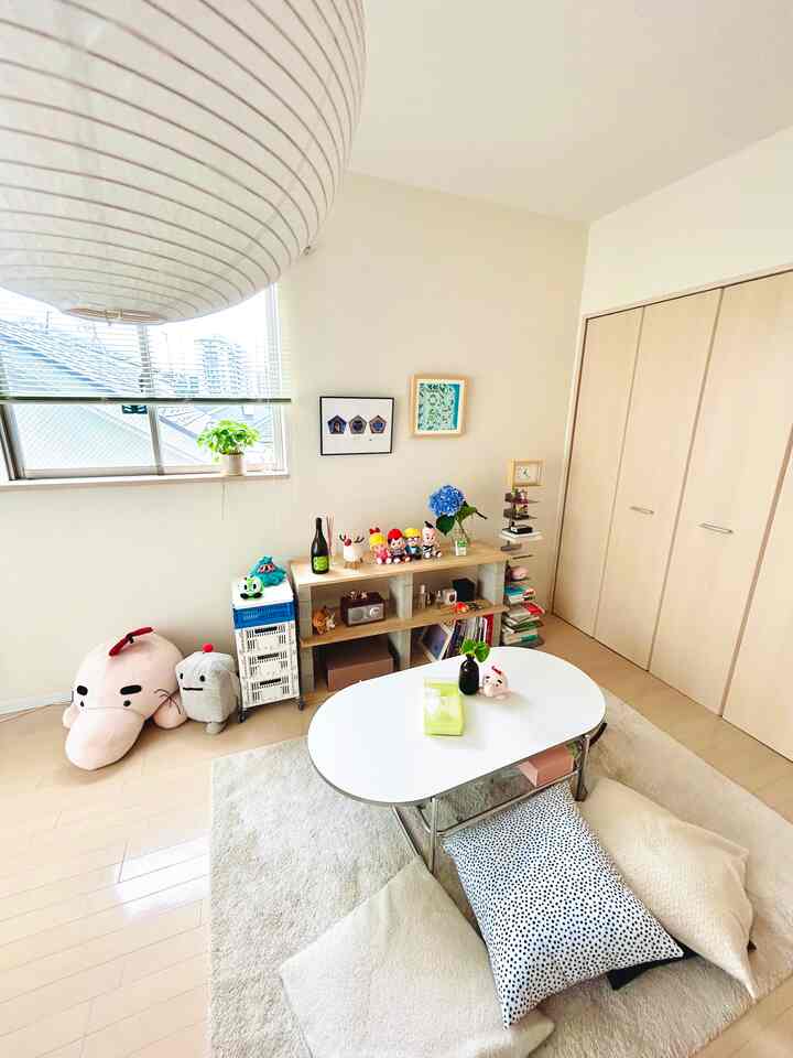 Bright white and light wood toned small studio living room featuring a simple low coffee table with cushions creating a cozy atmosphere