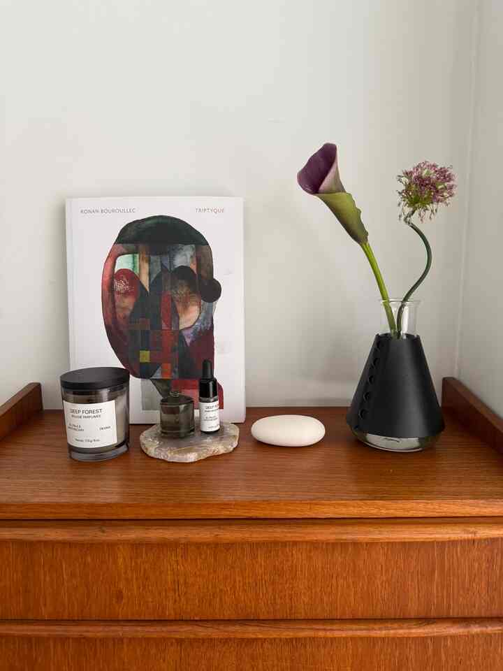 ナチュラルな木目調の北欧ヴィンテージチェストの上にアロマキャンドル、花瓶、オブジェがすっきりと配置されたミニマルなリビングインテリア