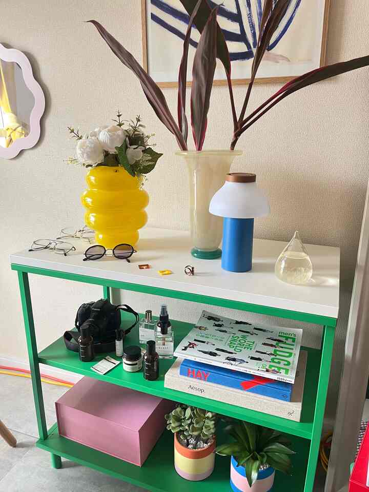 白い天板と緑の棚に黄色の花瓶や多様な小物が配置されたミッドセンチュリーモダンなインテリア