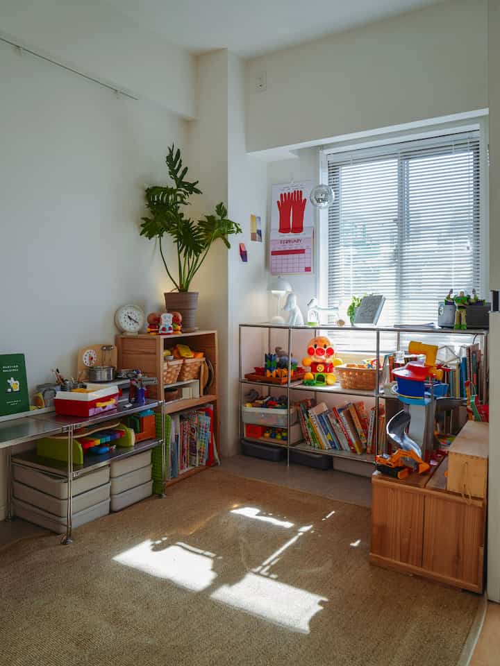 ナチュラルカラーとホワイトトーンの子供部屋、さまざまなおもちゃと本が棚に並べられた明るく清潔感のある印象的な空間