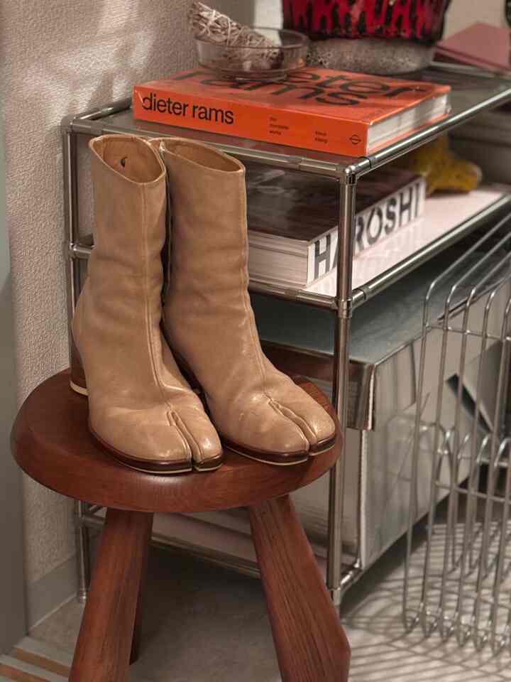 Beige boots on a wooden stool beside a metal shelf in a cozy living room corner