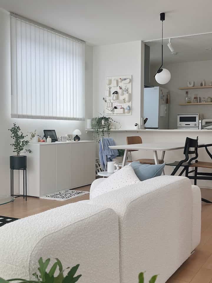 明るいホワイトトーンのモダンなリビングとダイニングルーム、木目調の床と多様なダイニングチェアが調和した清潔感のある空間