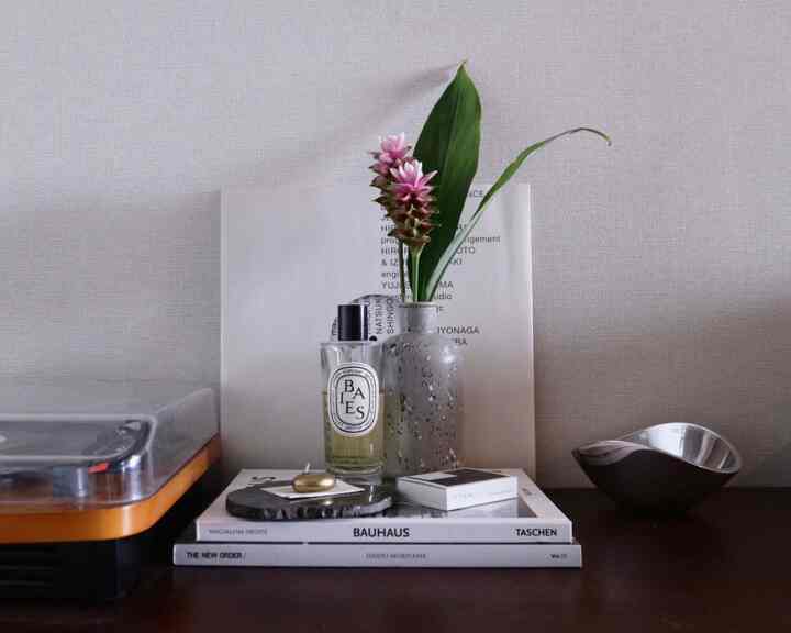 淡いグレーの背景に花瓶と本、ターンテーブルを配したミッドセンチュリーモダンのワークスペース